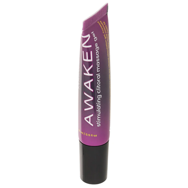 A close-up, angled studio shot of the "Awaken" stimulating clitoral massage gel tube standing upright against a white background. The front of the glossy purple squeeze tube is visible, showing the vertical white and pink "AWAKEN" branding and its black plastic cap at the bottom.