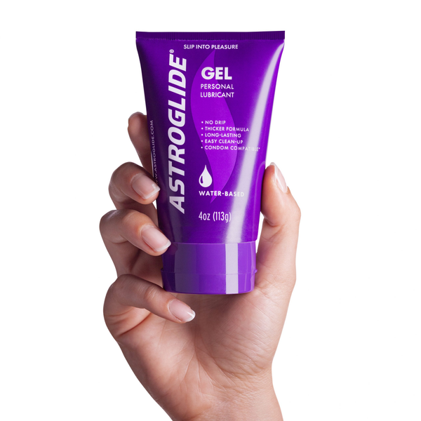 A hand with neutral-colored fingernails holding the purple tube of Astroglide Gel Personal Lubricant, 4 oz.