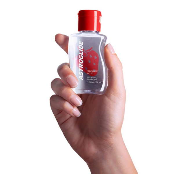 A hand holding a small, clear bottle of Astroglide Strawberry Liquid Personal Lubricant, 2.5 fl. oz.