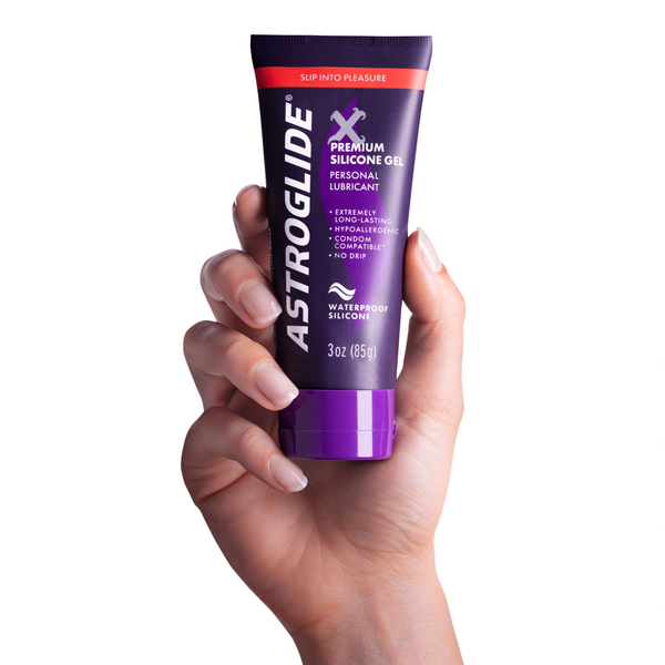 A hand holding a purple tube of Astroglide X Premium Silicone Gel Personal Lubricant, 3 oz (85g).
