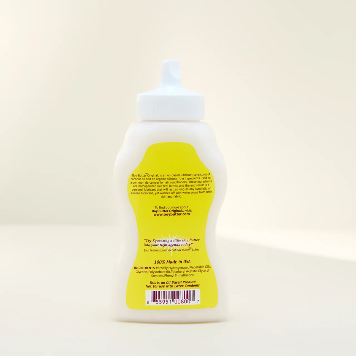 A shot showing the back label of the Boy Butter Original Personal Lubricant in a white, contoured, squeeze bottle with a white nozzle. The yellow label details the product's oil-based composition, its uses, and a warning that it is Not for use with Latex Condoms.
