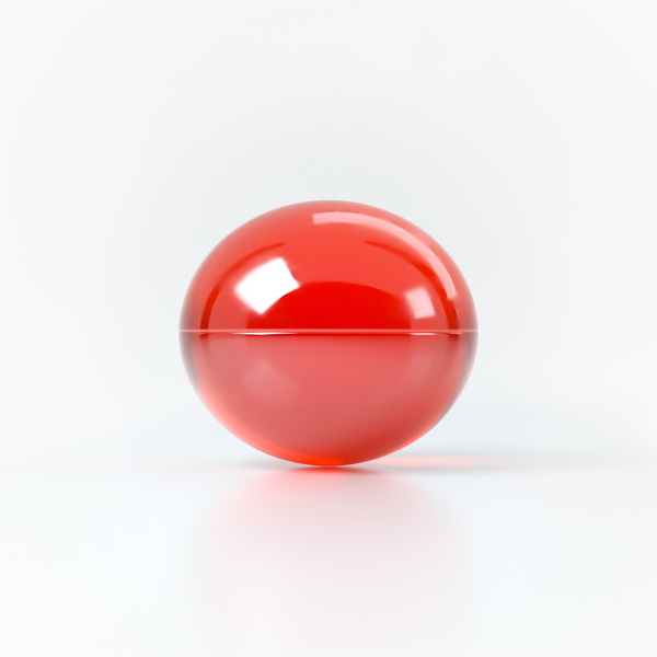 Studio product shot focusing on a single translucent red oil sphere resting on a clean white reflective surface.