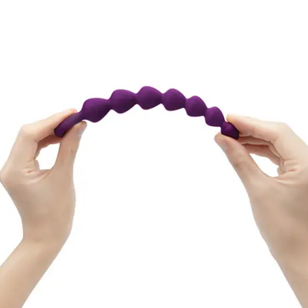 Flexibility demonstration photo showing hands bending the flexible purple silicone shaft of the anal beads into an arch.