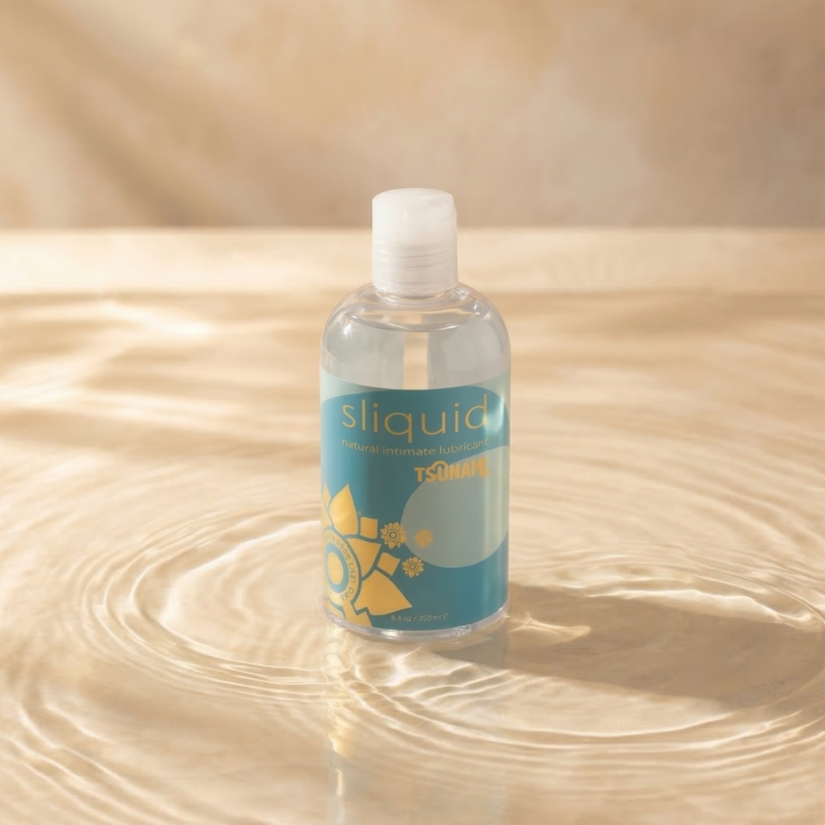 Studio display photo of a clear bottle of Sliquid Tsunami natural intimate lubricant sitting in shallow, rippling water.