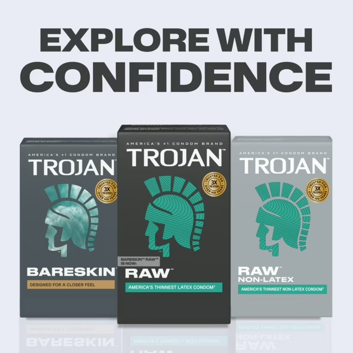 A promotional line-up display titled "EXPLORE WITH CONFIDENCE" in large dark grey text. Three different Trojan product boxes stand side-by-side reflecting slightly on a white surface. From left to right: a grey box of "BARESKIN" (Designed for a closer feel), a black box of "RAW" (America's thinnest latex condom), and a light grey box of "RAW NON-LATEX" (America's thinnest non-latex condom). Each features the signature helmet logo in a distinct colorway matching its box style.