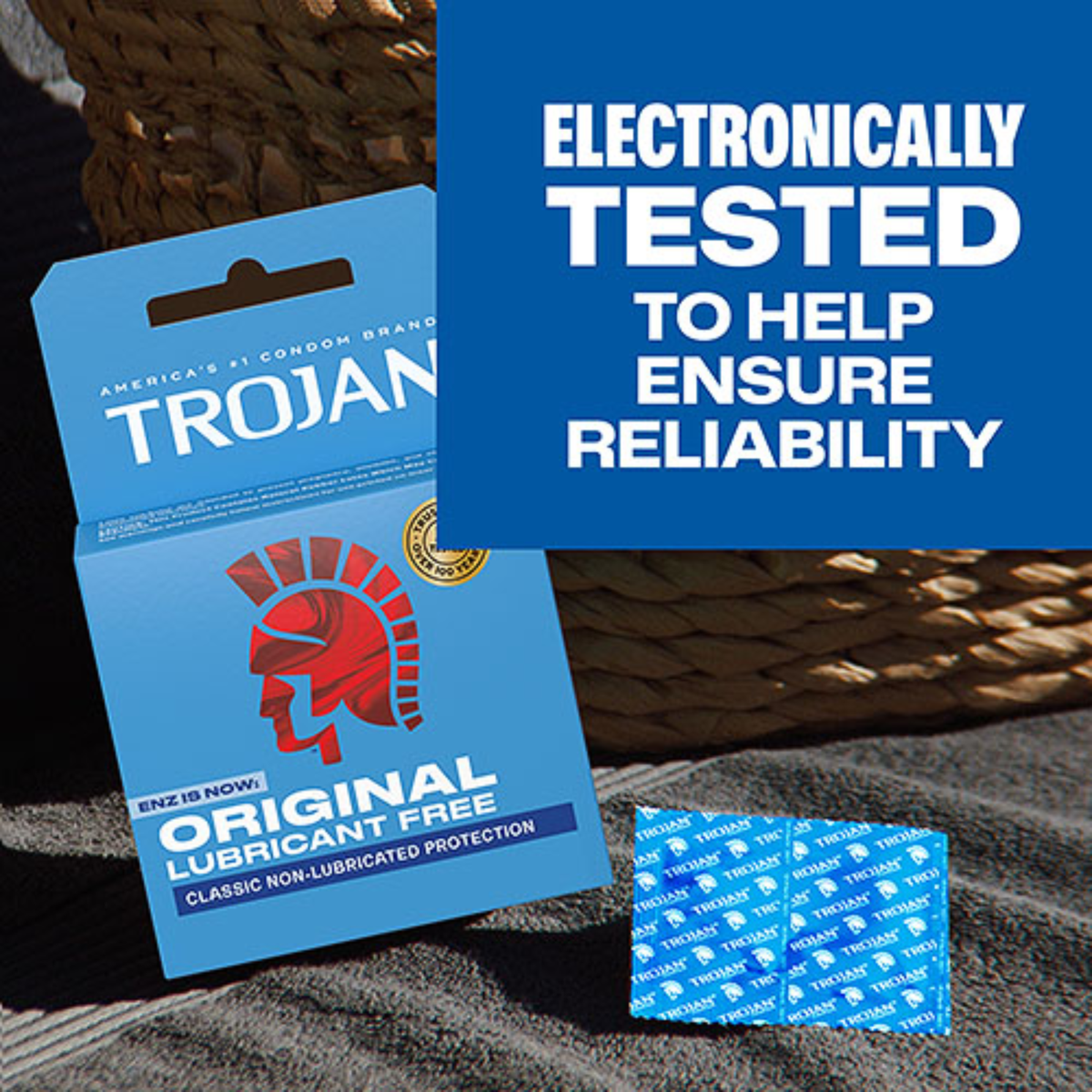 A close-up of the box and two blue foil condom wrappers on a textured surface. Large text on the right reads: "ELECTRONICALLY TESTED TO HELP ENSURE RELIABILITY."